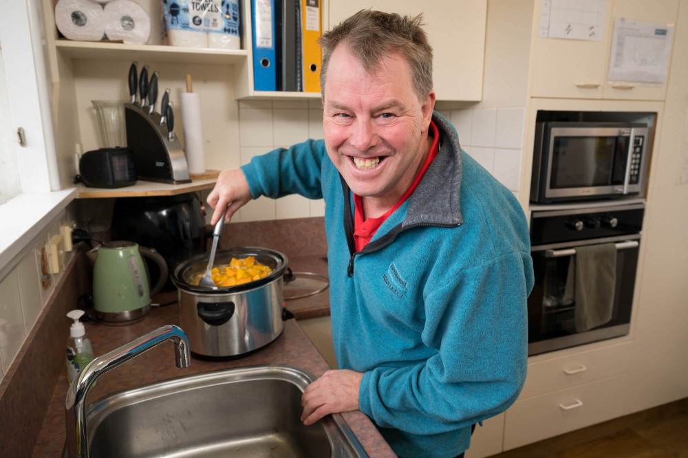 a person stirring food in a slow cooker and smiling
