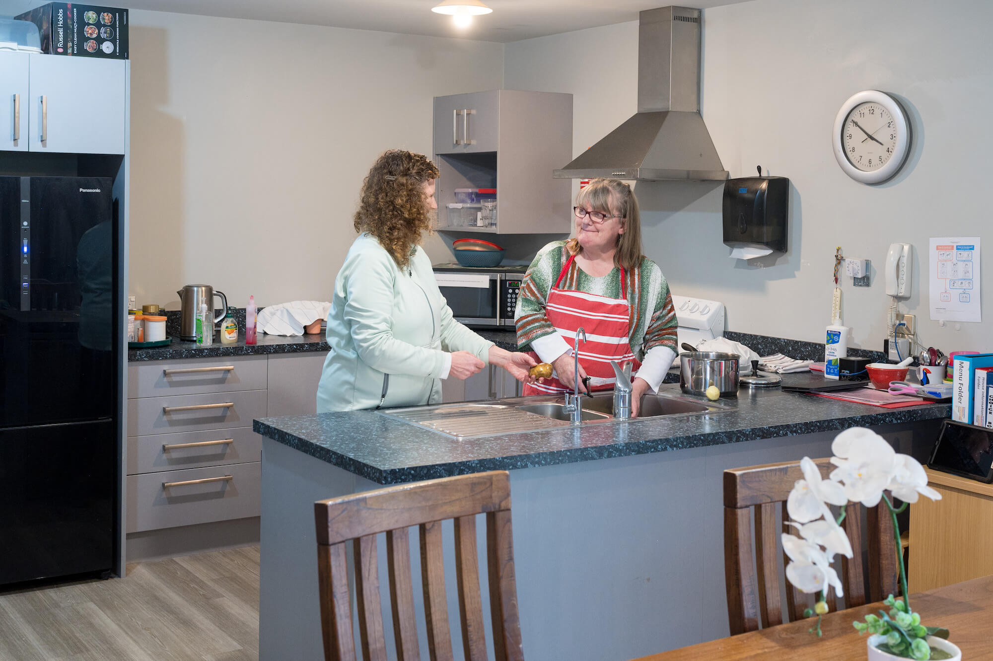 people in a kitchen peeling potatoes