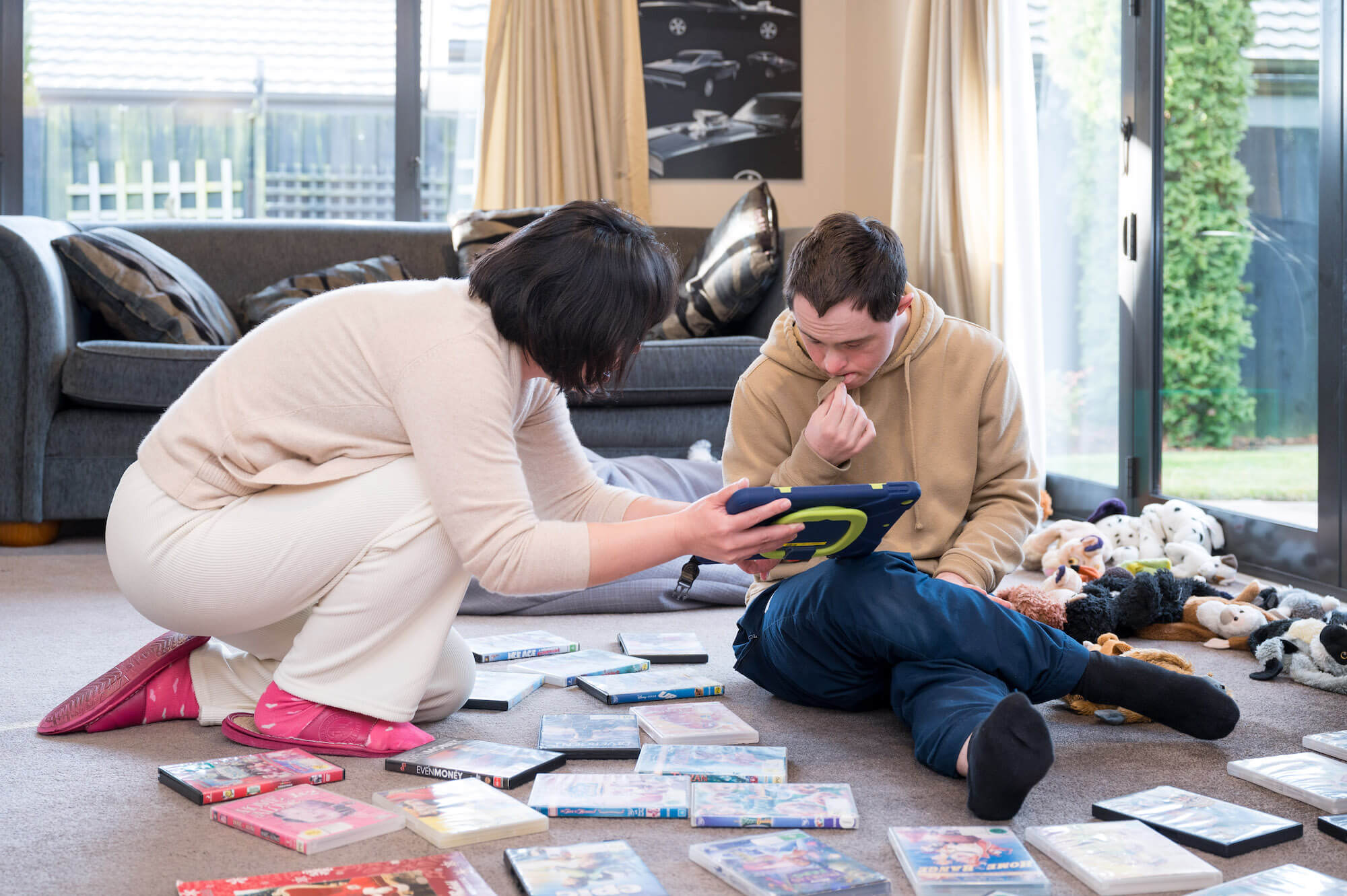 people looking at tablet with dvds around them on the floor